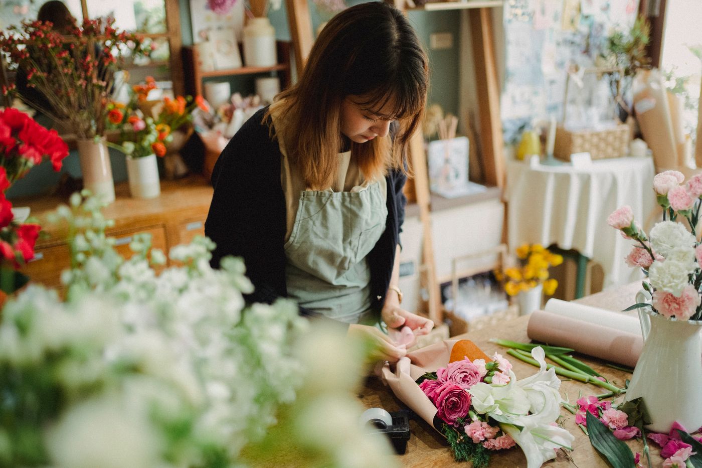 Une fleuriste compose un bouquet à son établi — photographie d’illustration